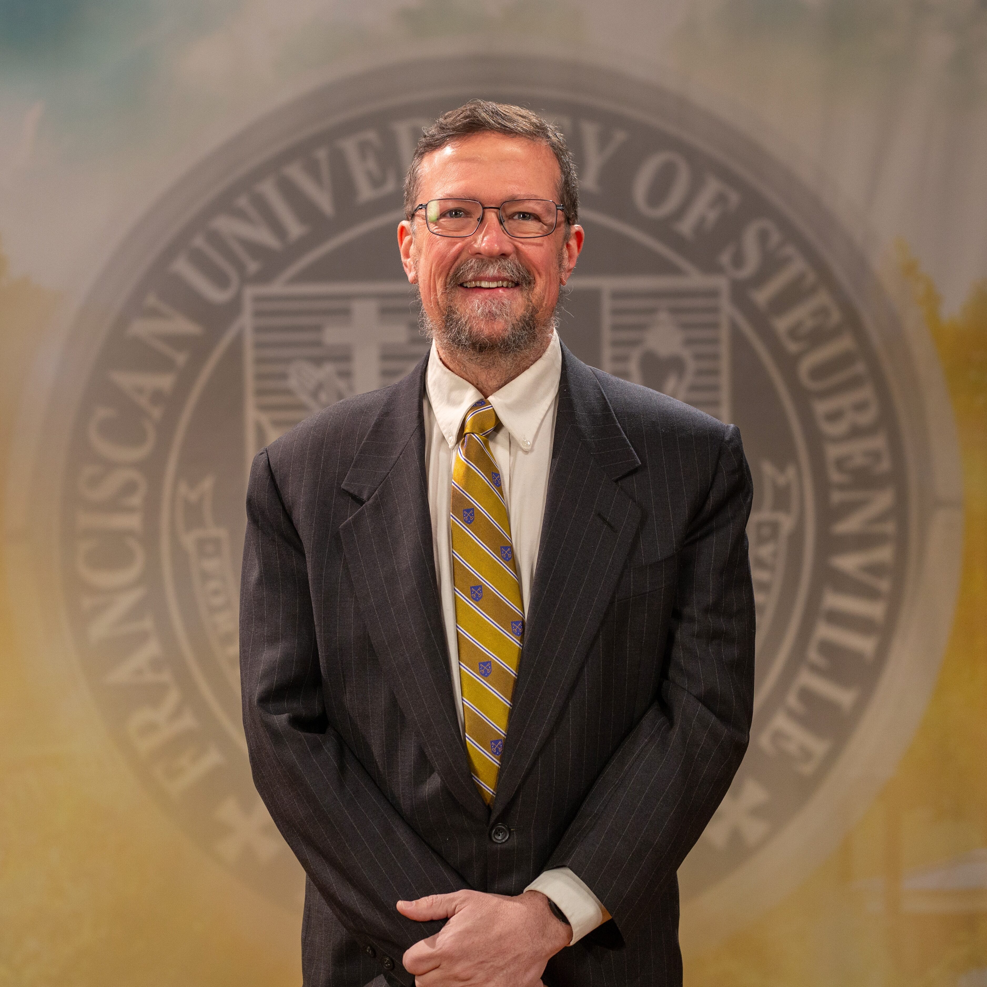 Dr. Michael Sirilla_Faculty Portrait_Spring2026_-2823 Faculty portrait of Dr. Michael Sirilla standing in front of the Franciscan University of Steubenville seal.