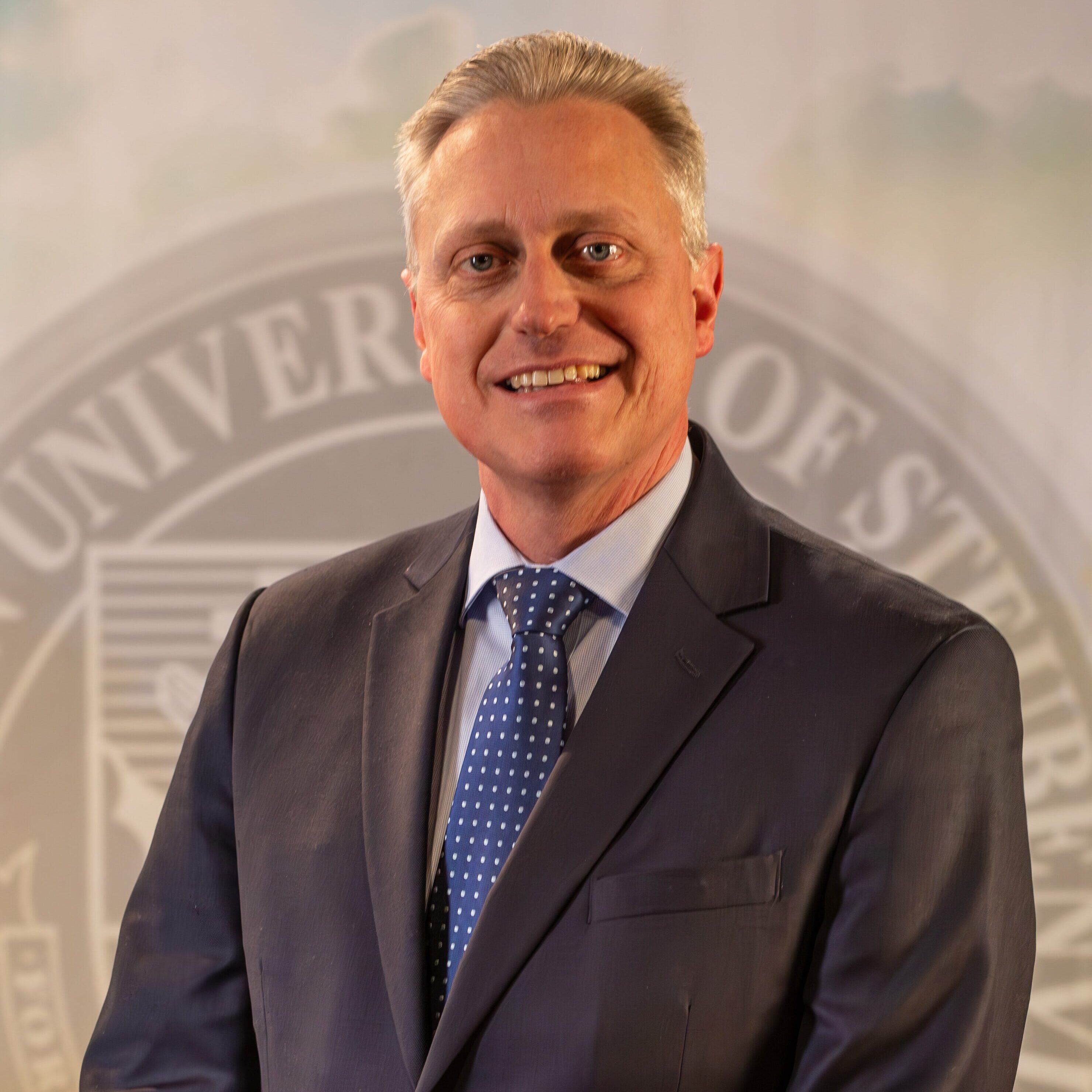 To Web – Dr. John Bergsma FEB2025 –4 Dr. John Bergsma standing in front of the Franciscan University of Steubenville seal.