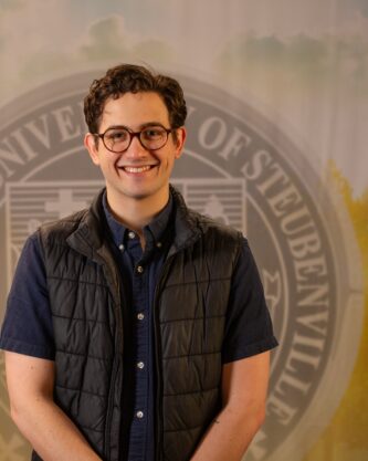 Nick Riccardi standing in front of a college seal.